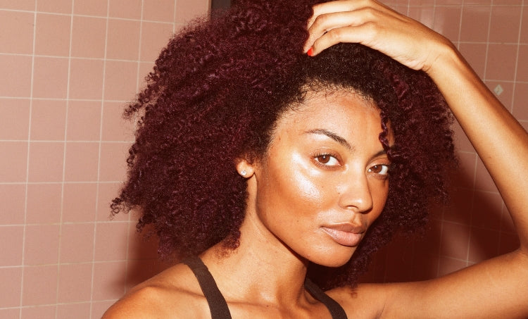 Close-up of woman with defined 3C curly hair and glowing skin, showing healthy texture and natural confidence.”